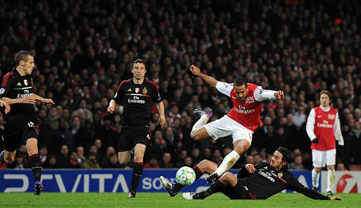 Pemain Arsenal, Theo Walcott menghindari tekel pemain AC Milan pada laga Liga Champions di Stadion Emirates, Selasa (6/3/2015). Kecepatan Walcott kerap merepotkan barisan pertahanan lawan. (AFP Photo/Adrian Dennis)