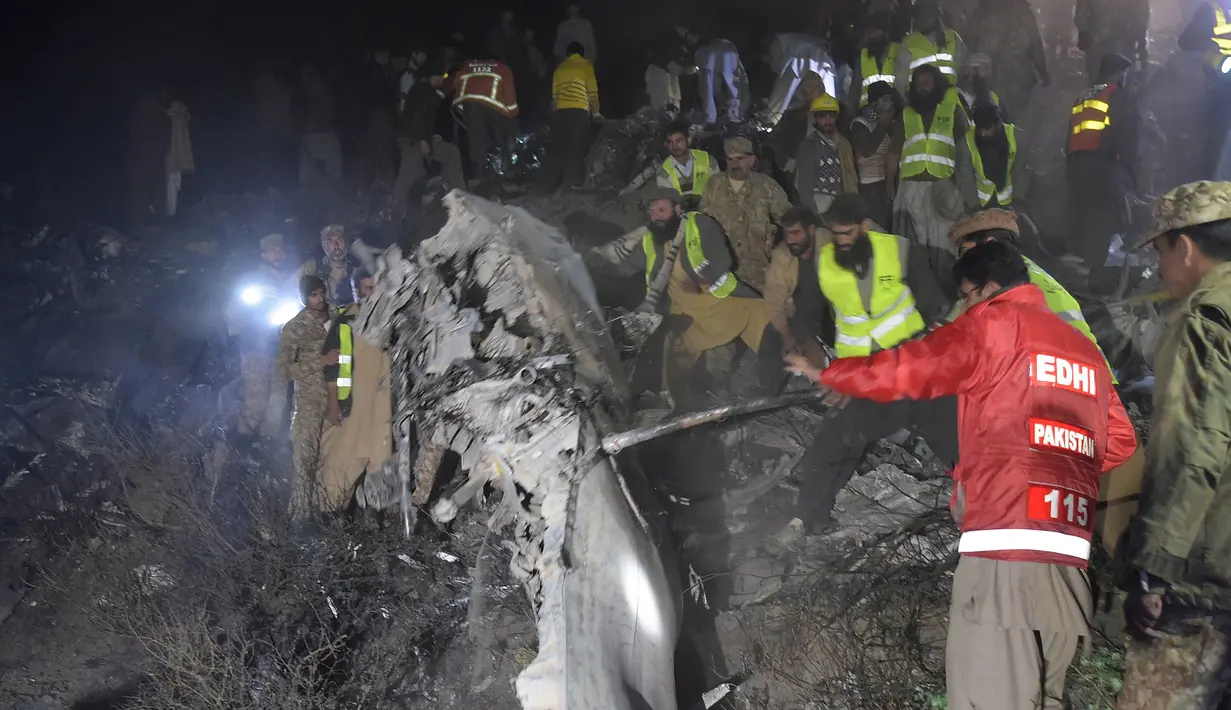Regu penyelamat mencari korban di antara puing pesawat Pakistan International Airlines yang jatuh di Abbottabad, wilayah Khyber Pakhtunkhawa, Rabu (7/12). Otoritas setempat menyatakan pesawat jatuh di gunung lalu meledak dan terbakar. (AAMIR QURESHI/AFP)