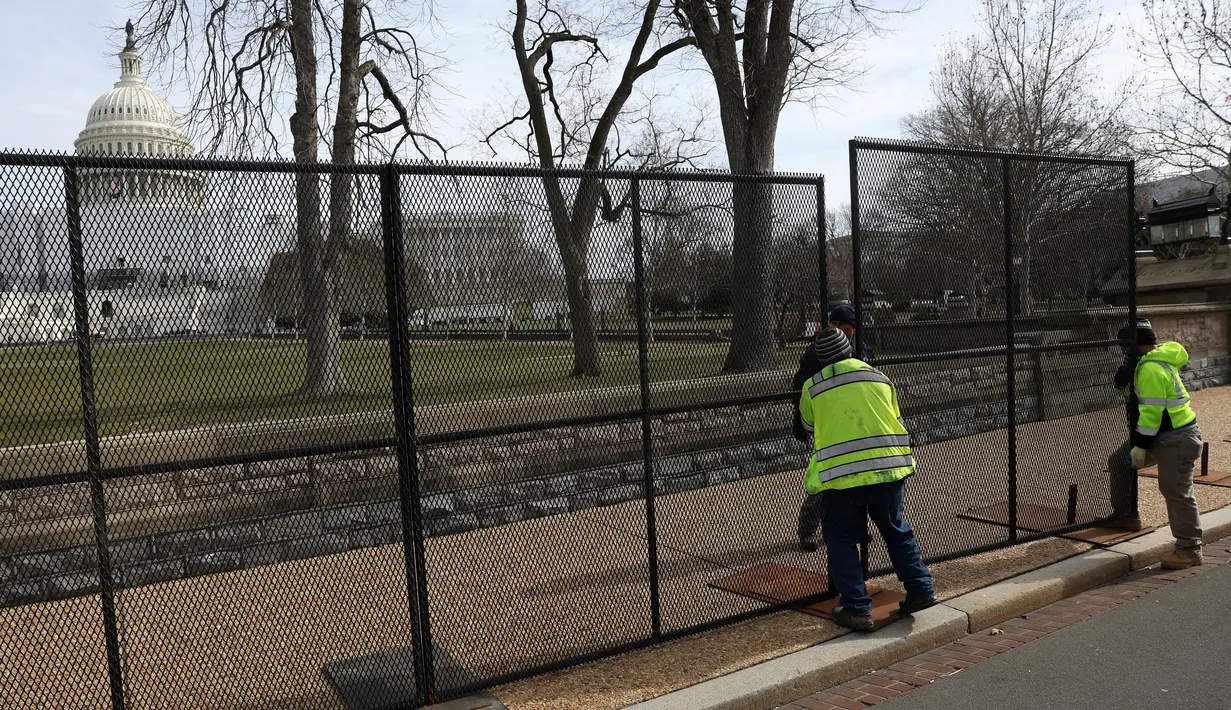 Para pekerja memasang pagar pengaman di sekitar U.S. Capitol di Washington, DC pada Minggu (5/2/2023). Pagar sedang dipasang sebagai bagian dari langkah-langkah keamanan yang ditingkatkan menjelang pidato kenegaraan Presiden Joe Biden pada hari Selasa. (Kevin Dietsch/Getty Images/AFP)