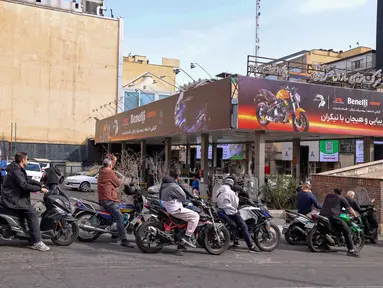 Orang-orang mengantre untuk mengisi bensin sepeda motor mereka di luar sebuah SPBU di Teheran, Iran pada Sabtu 28 Februari 2026. (Atta KENARE/AFP)
