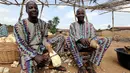 Si Kembar, Kehinde dan Taiwo Aderogba mengupas umbi singkong di pusat pengolahan di kota Igbo Ora, Negara Bagian Oyo, Nigeria pada 4 April 2019. Hingga kini, belum diketahui secara pasti mengapa tingkat kelahiran anak kembar sangat tinggi di sana. (REUTERS/Afolabi Sotunde)