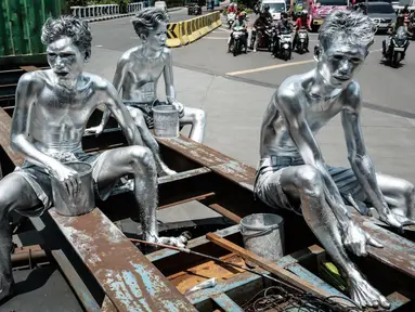 Foto yang diambil pada 7 April 2025 ini menunjukkan manusia silver Keris Munandar (kanan), saudaranya Ari Munandar (kiri), dan tetangganya Riyan Ahmad Fazriyansah menumpang di bagian belakang truk kontainer untuk mencapai persimpangan di Jakarta. (Yasuyoshi CHIBA/AFP)