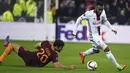 Penyerang Lyon, Alexandre Lacazette (kanan) berusaha melewati bek AS Roma, Federico Fazio pada leg pertama babak 16 besar Liga Europa di Stade de Lyon, Prancis, (9/3). Lyon berhasil mengalahkan AS Roma dengan skor 4-2. (AFP Photo / Philippe Desmazes)