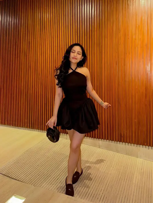 Girly dan manis, Rachel Vennya pakai mini dress hitam. Detail mini dressnya memiliki tali halter, ia juga mengenakan alas kaki dan menenteng mini bag yang sama-sama berwarna hitam. [Foto: Instagram/rachelvennya]