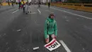 Seorang demonstran beristirahat dengan membawa poster bertuliskan "No more dictatorship," selama unjuk rasa di Caracas, Venezuela, (6/4). (AP Photo / Fernando Llano)