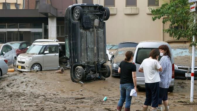 Sebuah mobil berdiri secara vertikal di jalan berlumpur setelah tersapu banjir di Hitoyoshi, prefektur Kumamoto, barat daya Jepang, Minggu (5/7/2020). Hujan deras di wilayah Kumamoto memicu banjir dan tanah longsor pada Sabtu dan menyebabkan banyak warga yang terisolasi. (Kyodo News via AP)