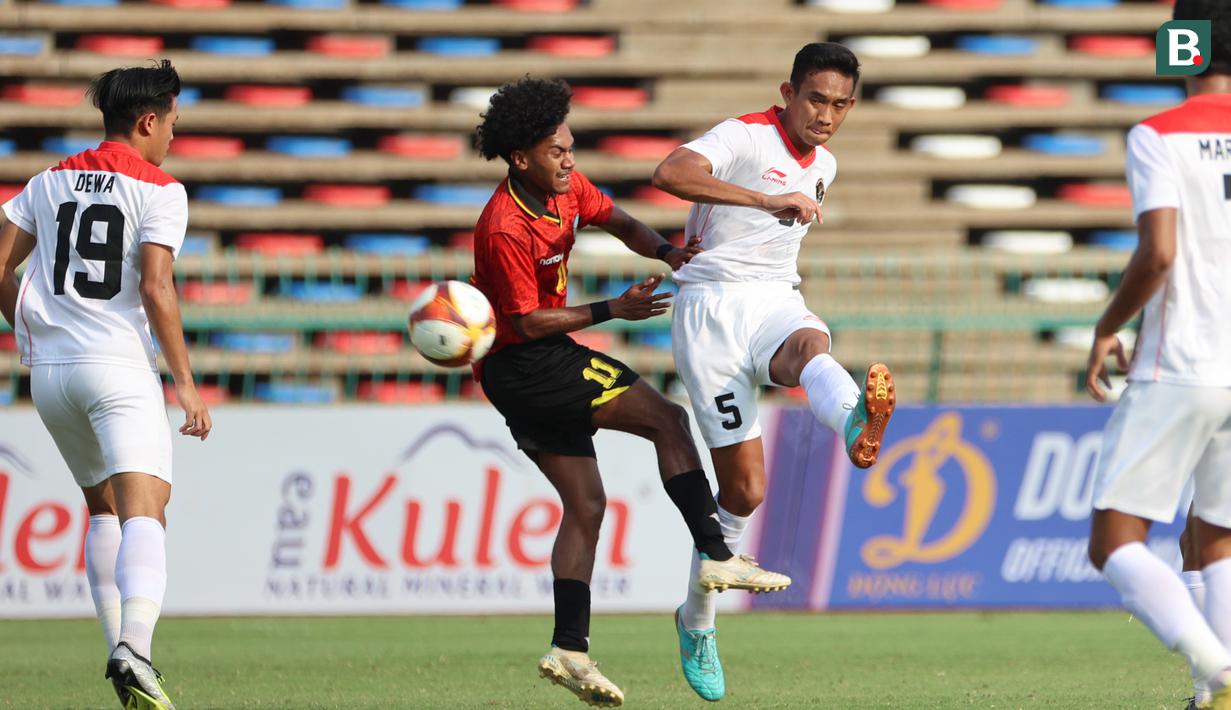 <p>Pemain Timnas Indonesia U-22,&nbsp;Rizky Ridho (kanan),&nbsp;menendang bola dibayangi pemain Timor Leste,&nbsp;Zenevio Morientes Gostavo Conceicao Mota pada pertandingan ketiga Grup A SEA Games 2023 yang berlangsung di Olympic Stadium, Phnom Penh, Kamboja, Minggu (7/5/2023). (Bola.com/Abdul Aziz)</p>