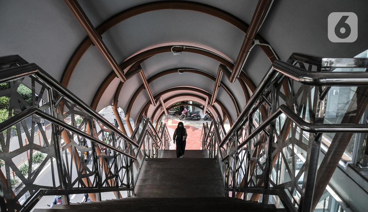 Pejalan kaki menggunakan fasilitas jembatan penyeberangan orang (JPO) di Jalan Kolonel Sugiono, Duren Sawit, Jakarta Timur, Senin (7/2/2022). JPO Kolonel Sugiono yang berada dekat Kanal Banjir Timur itu didesain dengan bentuk yang modern namun sarat kearifan lokal. (merdeka.com/Iqbal S Nugroho)