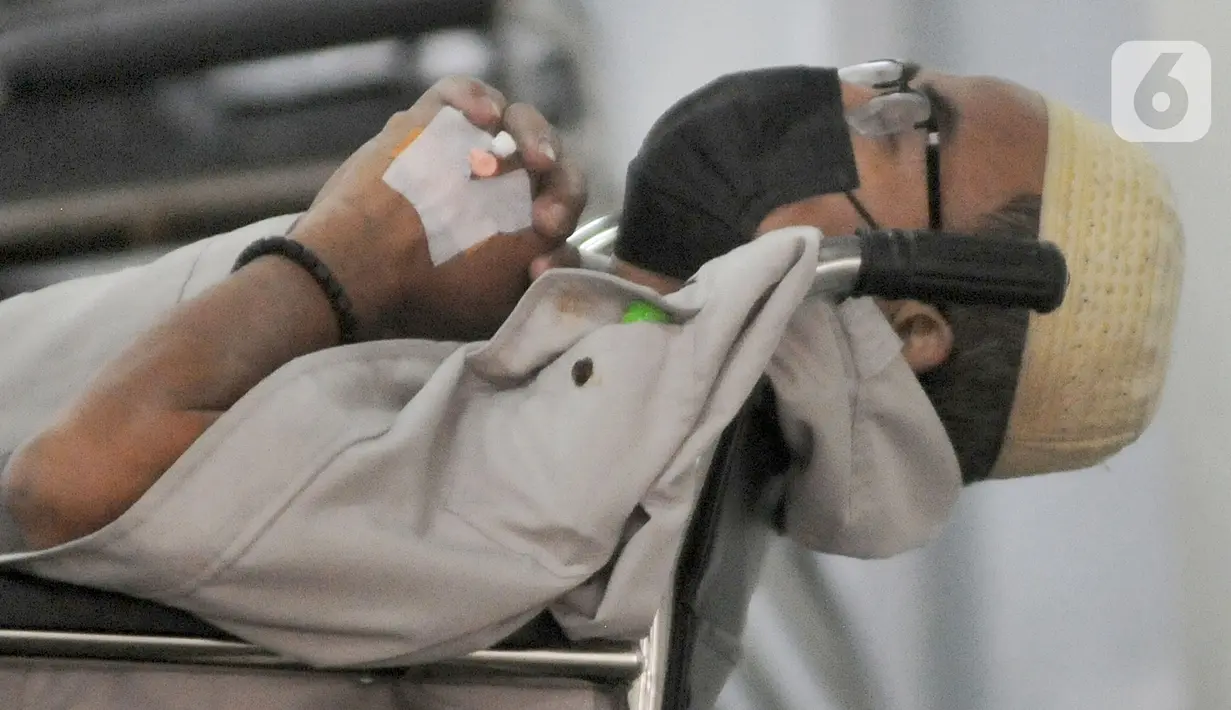 Pasien COVID-19 menunggu di kursi roda untuk mendapatkan kamar perawatan di depan UGD RSUD Cengkareng, Jakarta, Kamis (24/6/2021). Lonjakan kasus virus corona mengakibatkan ruang IGD penuh, pihak rumah sakit lantas mendirikan tenda darurat untuk merawat pasien covid-19. (merdeka.com/Arie Basuki)