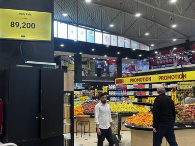 Pelanggan berjalan melewati layar yang menunjukkan kurs dolar AS harian di sebuah supermarket di Beirut, Rabu (1/3/2023). Lebanon mulai memberi harga barang-barang di supermarket dalam dolar AS pada Rabu karena nilai pound Lebanon mencapai posisi terendah baru. (AP Photo/Hussein Malla)