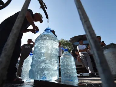 Warga Kyrgyz mengambil air dari mata air artesis di sebuah masjid dekat distrik Archa-Beshik di ibu kota Bishkek pada 8 Juni 2023. Penduduk ibu kota Kyrgyz berkumpul di sekitar lubang bor dengan botol plastik, satu-satunya cara bagi mereka untuk mendapatkan air setelahnya awal musim panas yang kering. (VYACHESLAV OSELEDKO / AFP)