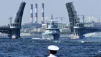 Seorang pelaut menyaksikan kapal perang Rusia berlayar selama parade Hari Angkatan Laut di Sungai Neva, Saint Petersburg, Rusia, Minggu (29/7). (Kirill Kudryavtsev/AFP)