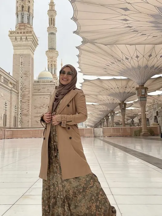 Berada di tanah suci, Dine dengan long coat cokelat yang dipadu abaya bermotif cokelat. Credit: Instagram @dine.pearl