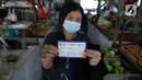 Warga menunjukkan kartun vaksin COVID-19 di Pasar Gang Kancil, Taman Sari, Jakarta Barat, Senin (2/8/2021). Gubernur Anies Baswedan mengatakan pemprov DKI telah memenuhi target Presiden Joko Widodo untuk menyalurkan vaksinasi Covid-19 dosis pertama kepada 7,5 juta orang. (Liputan6.com/Faizal Fanani)