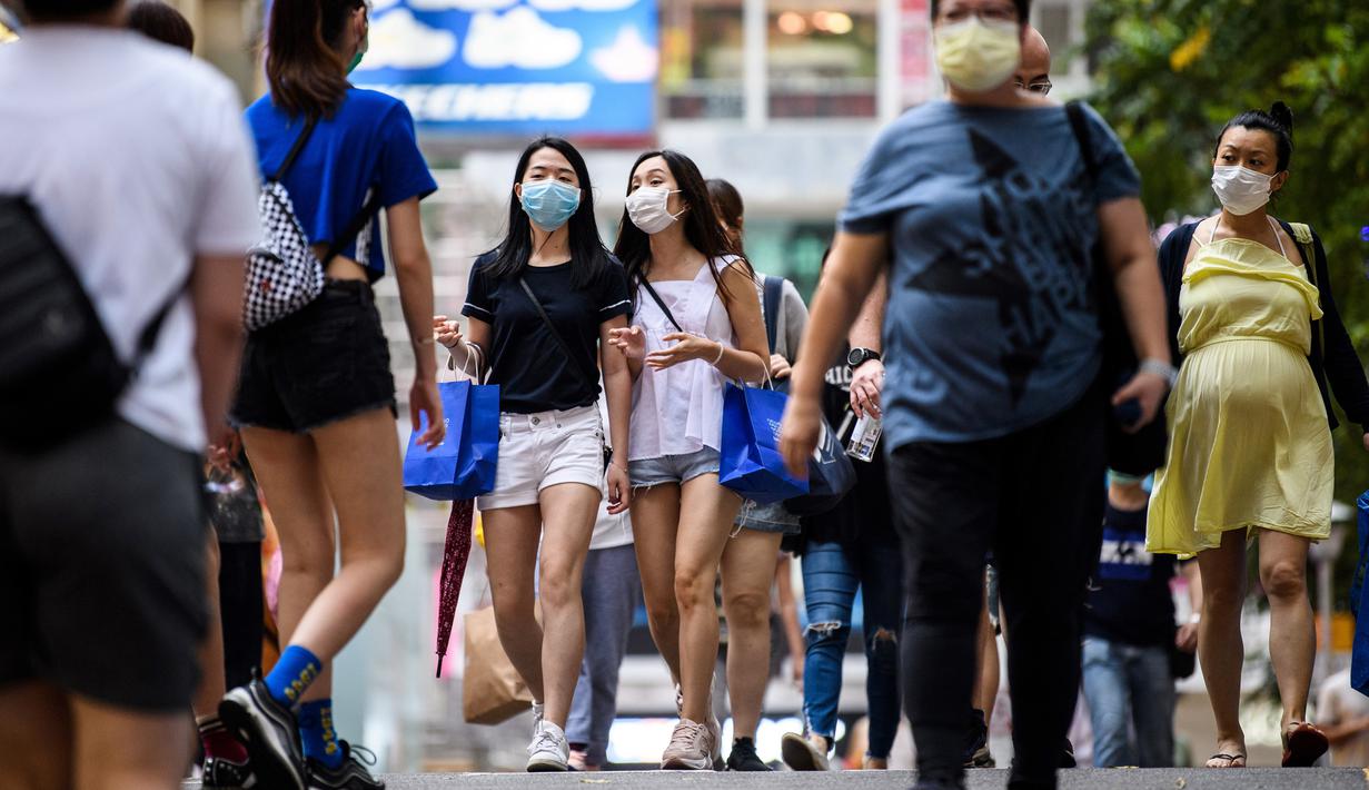 Dua wanita mengenakan masker sebagai tindakan pencegahan Covid-19 saat berjalan di Hong Kong (13/5/2020). Dua orang di Hong Kong dinyatakan positif Covid-19, mengakhiri perjalanan 24 hari tanpa kasus baru yang mulai melonggarkan peraturan jarak sosial. (AFP/Anthony Wallace)