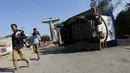 Warga berjalan di dekat kendaran yang terbalik akibat demonstrasi di negara bagian Haryana, India,Minggu (21/2). Pihak berwenang mengambil langkah mengatasi masalah pasokan air yang menimbulkan aksi kekerasan yang menewaskan 10 orang (REUTERS/Adnan Abidi)