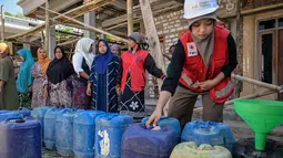 Warga antri saat pendiistribusian air  bersih oleh Palang Merah Indonesia (PMI) Kabupaten Bangkalan di Dusun Batangan Tengah, Desa Batangan, Kecamatan Tanah Merah, Kabupaten Bangkalan, Jawa Timur, Selasa (21/7/2026). (AFP/ Juni Kriswanto)