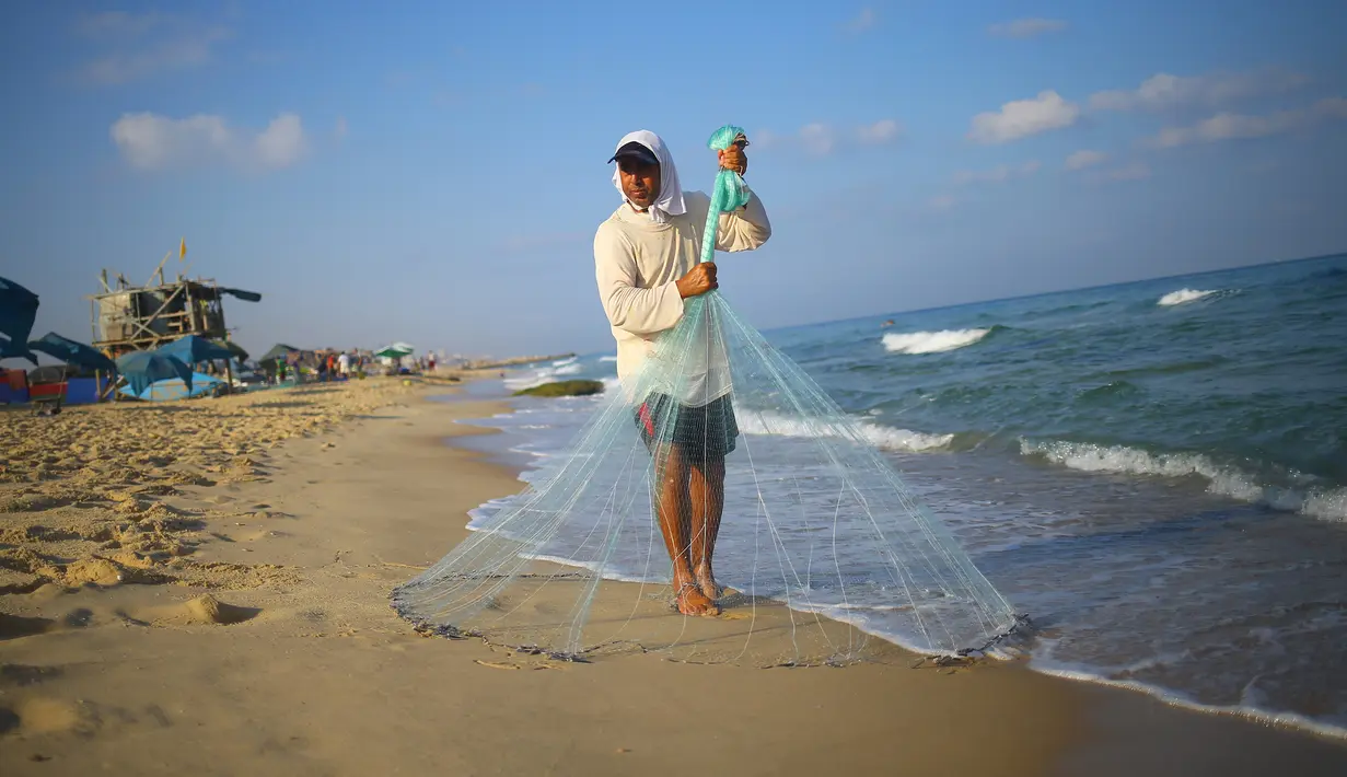 Nelayan Palestina, Jihad al-Soltan mencari ikan dengan melempar jala di pantai kawasan Beit Lahia, Jalur Gaza, Selasa (22/8). Soltan menemukan botol surat yang dihanyutkan pasangan Inggris yang tengah berlibur di Pulau Rhodes, Yunani. (MOHAMMED ABED/AFP)