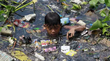 Seorang Anak laki-laki memilah sampah yang terapung untuk di jadikan bahan daur ulang di sebuah sungai yang tercemar di kota navotas, Manila, Kamis (2/7/2015). Daur ulang bertujuan untuk mengurangi tingkat pencemaran sungai. (REUTERS/Romeo Ranoco)