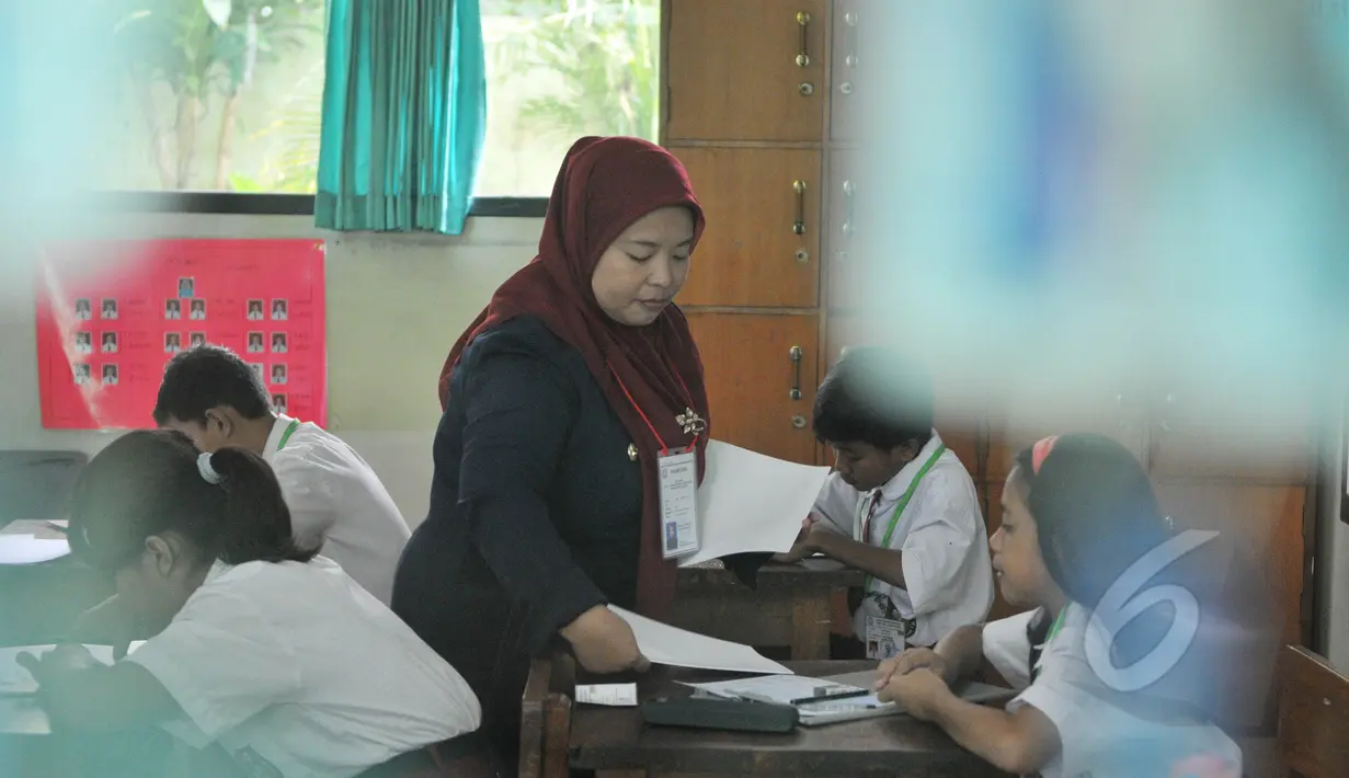 Seorang guru membagikan soal Ujian Nasional (UN) kepada para peserta di SDN 04 Jakarta, Senin (18/5/2015). Sebanyak 153.266 peserta didik SD/MI dan sederajat di Jakarta mengikuti UN yang digelar 18-20 Mei. (Liputan6.com/Herman Zakharia)
