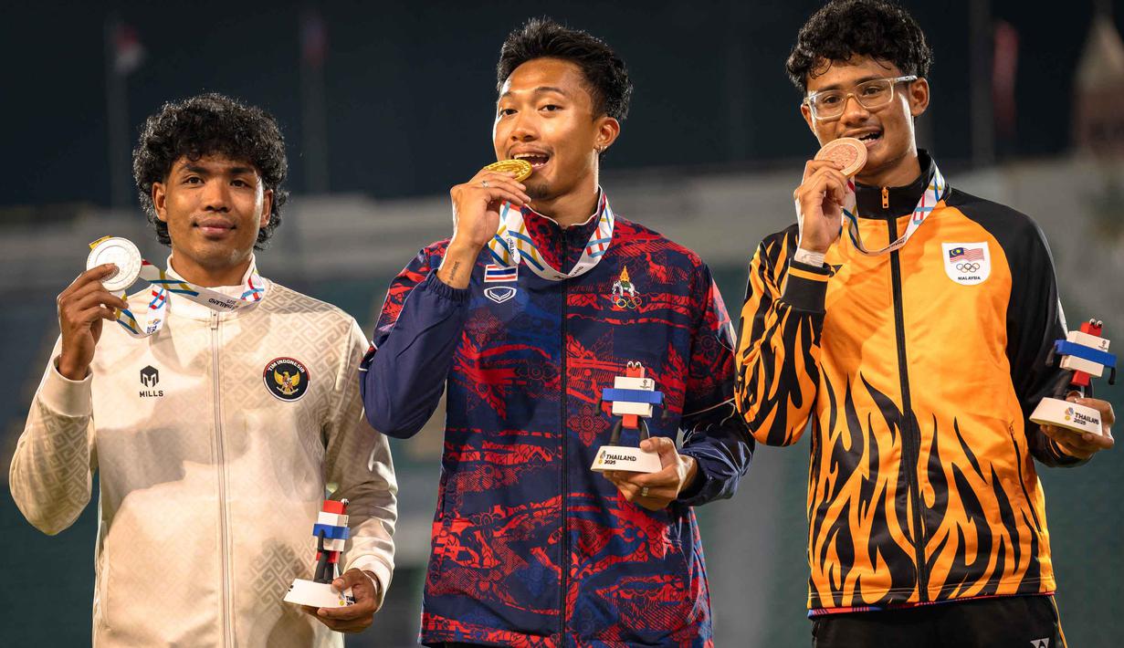 Ini menjadi hasil maksimal yang diraih Lalu Muhammad Zohri yang sedang mengalami cedera pada saat sebelum training camp dan sedang mengalami sedikit kendala di lutut kirinya. Tampak dalam foto, Puripol Boonson dari Thailand (tengah) berpose untuk foto dengan medali emasnya di samping peraih medali perak Lalu Muhammad Zohri dari Indonesia (kiri) dan peraih medali perunggu Danish Iftikhar Muhammad Roslee dari Malaysia setelah final 100 meter putra cabang atletik pada SEA Games ke-33 di Suphachalasai National Stadium, Bangkok, pada Kamis 11 Desember 2025. (Chanakarn LAOSARAKHAM/AFP)