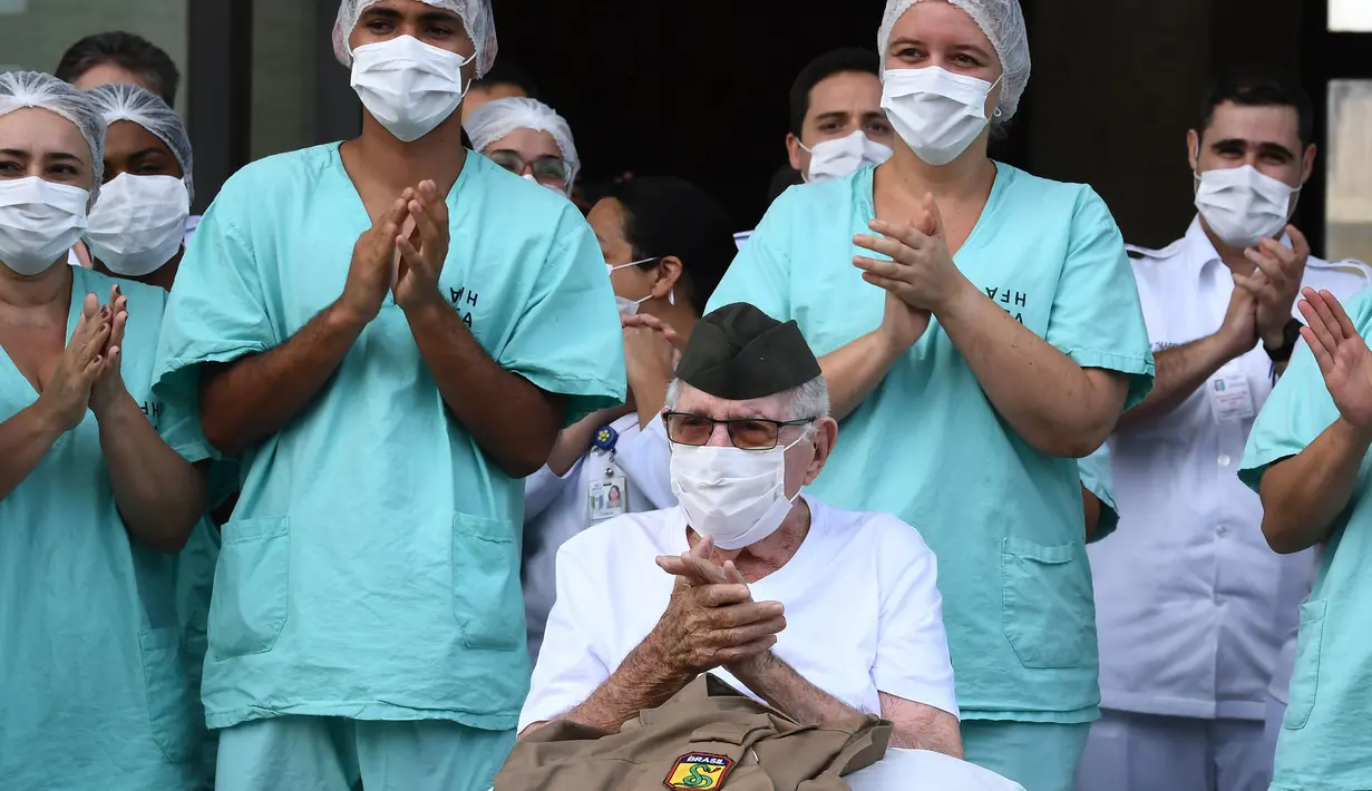 Veteran Perang Dunia II asal Brasil, Ermando Armelino Piveta meninggalkan Rumah Sakit Angkatan Bersenjata setelah pulih dari covid-19 di Brasilia, Selasa (14/4/2020). Mengenakan topi militer, kakek berusia 99 tahun tersebut mengangkat tangannya saat meninggalkan rumah sakit. (EVARISTO SA/AFP)
