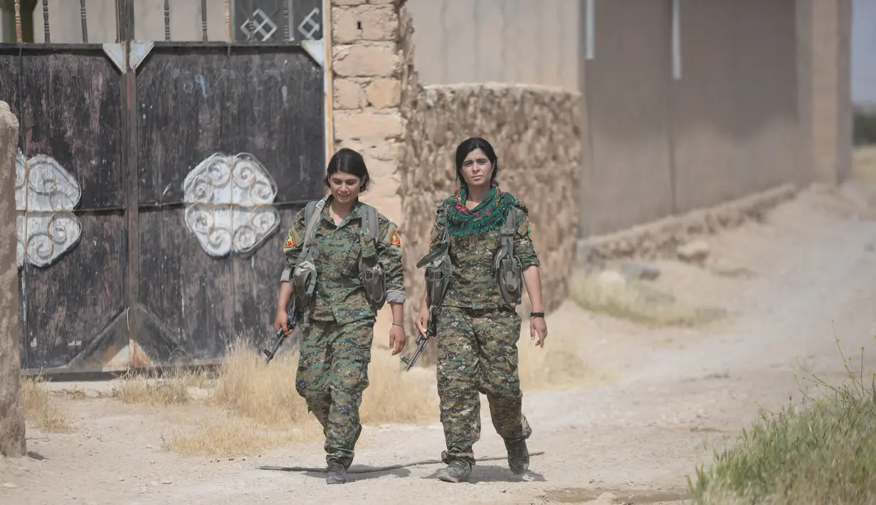 Dua prajurit perempuan Yazidi dari Unit Perlawanan Sinjar (YBS) berjalan saat patroli di sebuah jalan di wilayah Pegunungan Sinjai, Irak (6/6). (Reuters/Stringer)