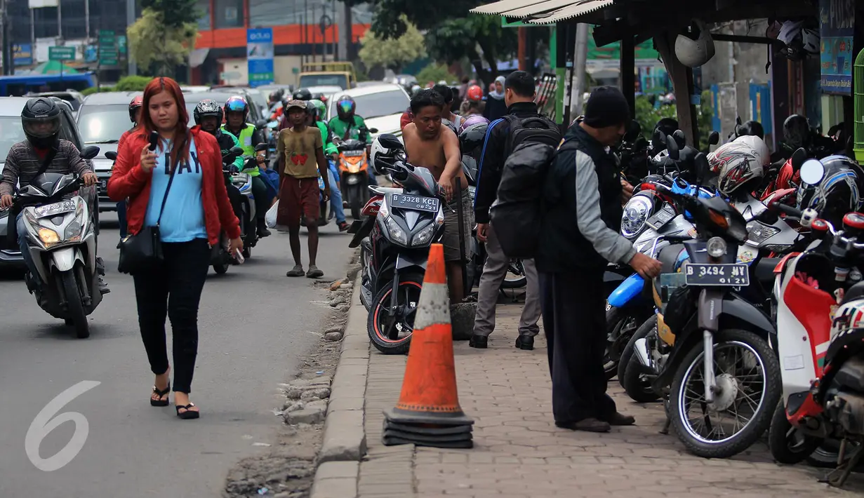 Warga melintas di samping trotoar yang dijadikan tempat parkir motor di Jalan Juanda, Bekasi, 4 Oktober 2016. Trotoar yang seharusnya untuk pejalan kaki ini dialih fungsikan oleh jasa parkir liar sebagai tempat parkir kendaraan bermotor. (Foto: Fajar)
