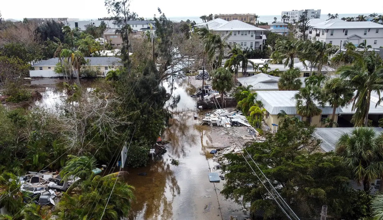 Foto udara memperlihatkan sebuah jalan yang tergenang air dan dipenuhi puing-puing setelah terjangan Badai Milton, di Siesta Key, Florida, pada tanggal 10 Oktober 2024. (CHANDAN KHANNA/AFP)