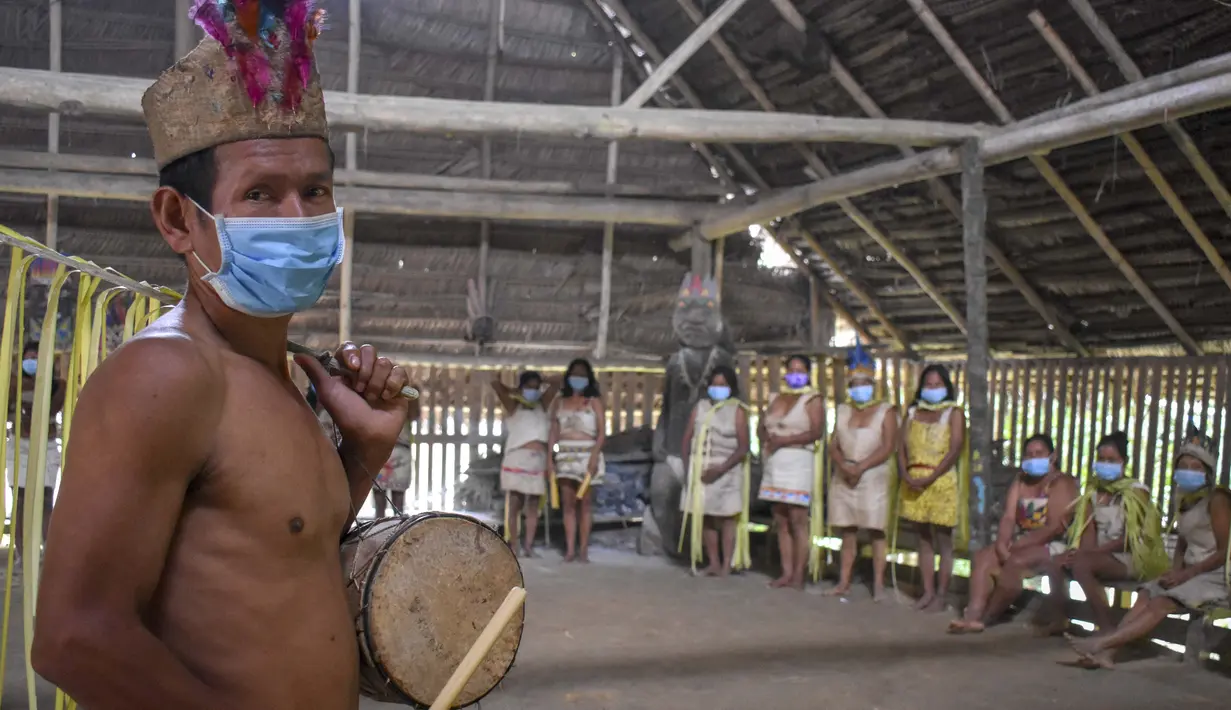 Suku Tikuna berpose mengenakan masker di tengah kekhawatiran virus corona Covid-19 di Leticia, Departemen Amazonas, Kolombia pada 8 Juni 2020. Kasus virus corona ini meningkatkan kekhawatiran akan resiko penyebaran ke masyarakat adat yang rentan dan berada di pedalaman. (Tatiana de NEVO/AFP)