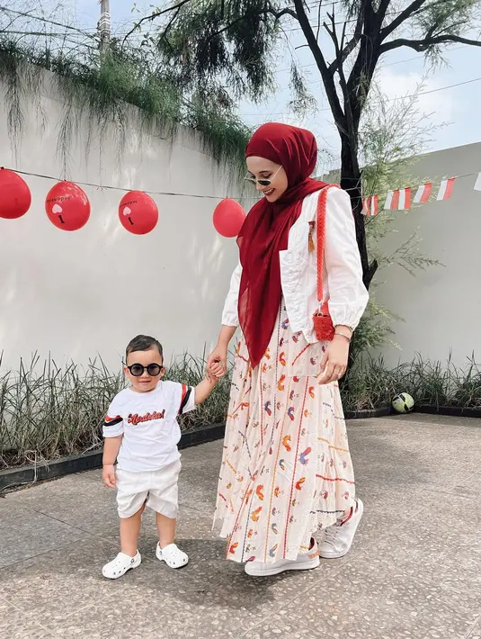 Memeriahkan HUT ke-77 RI, Zaskia Sungkar mengunggah foto bersama si kecil, Ukkasya. Kakak Shireen Sungkar itu mengenakan dress motif bernuansa peach dengan outer putih serta kerudung merah. Sementara Ukkasya tampil dengan kaos dan celana serba putih. (Instagram/zaskiasungkar15).