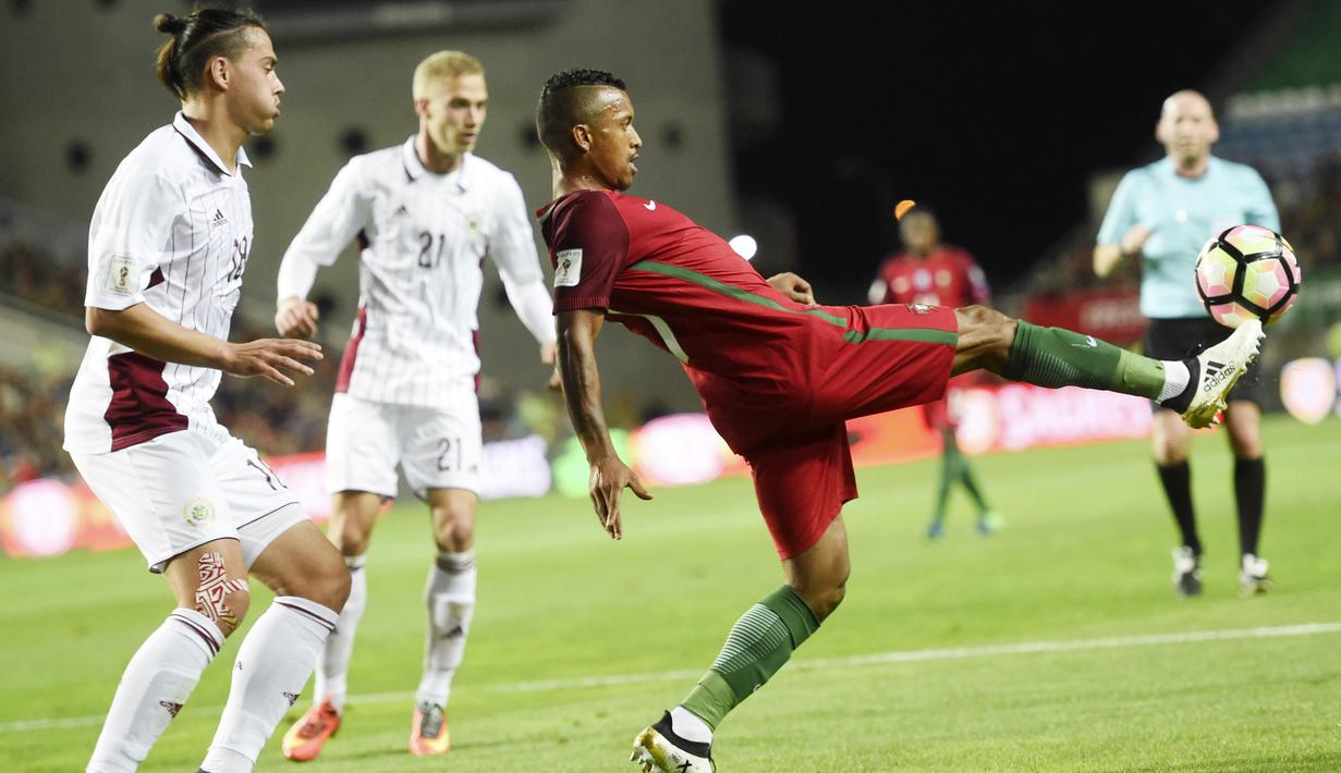 Pemain Portugal, Nani (kanan) berusaha menahan bola saat dihadang para pemain Latvia pada laga Kualifikasi Piala Dunia 2018 di Algarve stadium, Faro (13/11/2016). Portugal menang 4-1. (AFP/Francisco Leong)