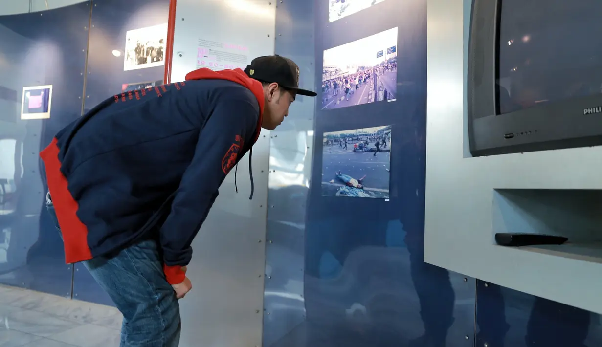 Pandji Pragiwaksono mengamati foto-foto tragedi Trisakti 1998 yang sampai menimbulkan korban jiwa di Kampus Universitas Trisakti, Jakarta Barat, Selasa (10/5/2016). (Adrian Putra/Bintang.com)