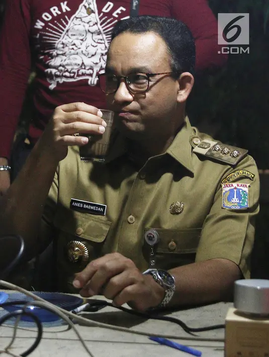 Gubernur DKI Jakarta Anies Baswedan menikmati kopi sambil berbincang dengan Pewarta Foto di Posko Pewarta Foto Bundaran HI, Jakarta, Selasa (13/11). (Liputan6.com/Herman Zakharia)