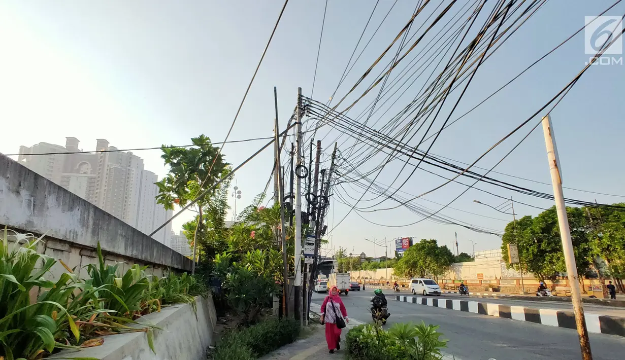 Instalasi kabel menjuntai yang berada di sekitar Jalan Gunung Sahari, Mangga Dua, Jakarta, Kamis (10/7/2019). Buruknya tata instalasi kabel di Ibu Kota menjadi penyebab banyaknya kabel semrawut, meskipun kondisi itu berbahaya serta mengganggu pemandangan. (Liputan6.com/Immanuel Antonius)