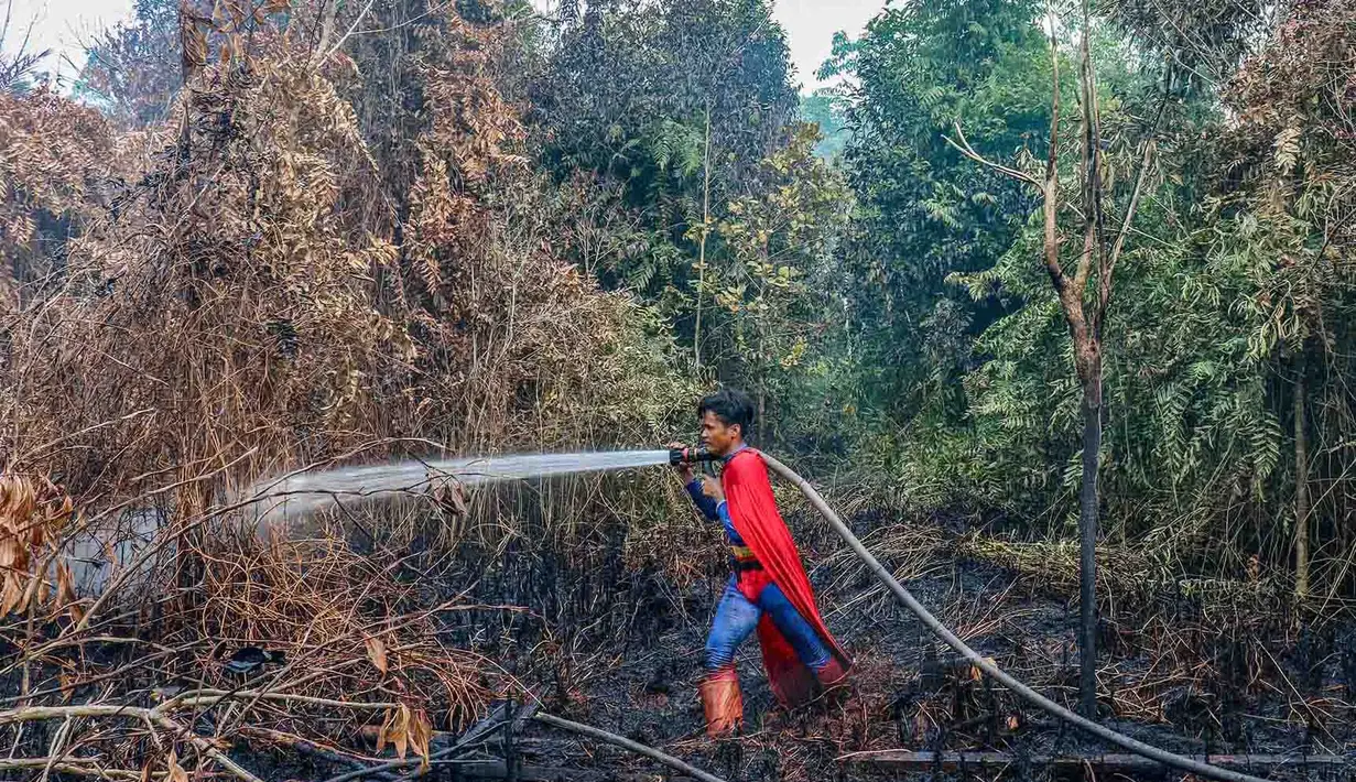 Pelajar bernama Rudiansyah dengan mengenakan kostum Superman membantu memadamkan kebakaran hutan dan lahan di Petuk Katimpun, Palangkaraya, Kalimantan Tengah, 17 Agustus 2026. (AFP/ Reina)