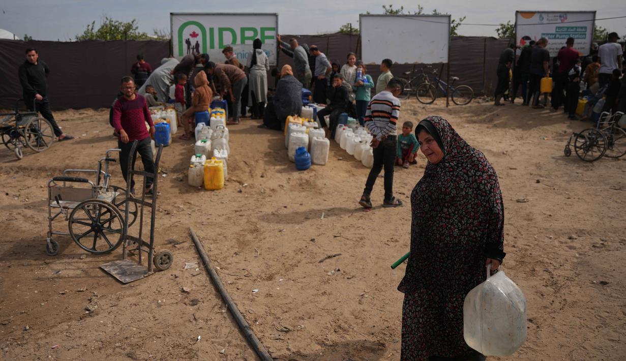 Keterbatasan bahan pangan, air bersih, serta padatnya lokasi pengungsian menciptakan kondisi rawan kelaparan dan penyakit. Tampak dalam foto, seorang wanita Palestina membawa jerigen berisi air yang dikumpulkan dari pabrik desalinasi, Khan Younis, Jalur Gaza selatan, Jumat 6 Februari 2026. (AP Photo/Abdel Kareem Hana)