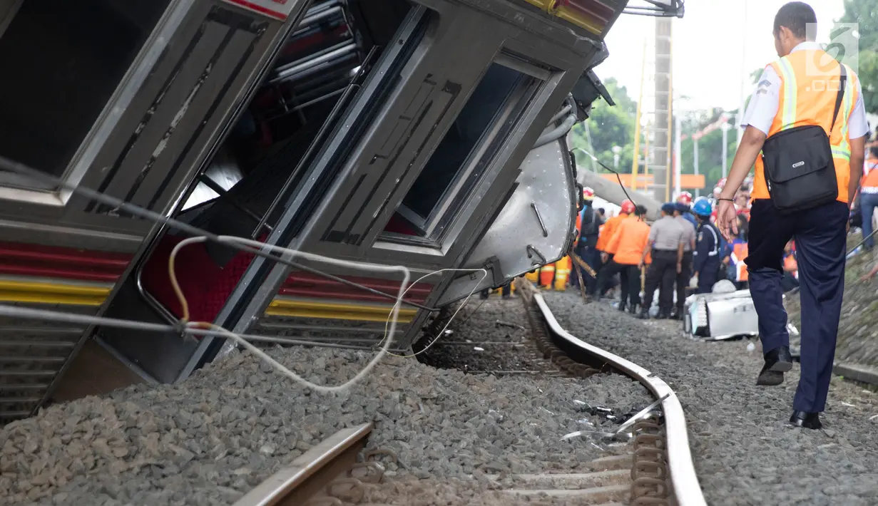Petugas berjalan di samping rangkaian KRL yang anjlok di perlintasan Kebon Pedes, Bogor, Jawa Barat, Minggu (10/3). Belum diketahui penyebab pasti anjloknya kereta. (Liputan6.com/Immanuel Antonius)