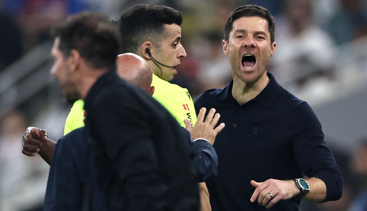 Xabi Alonso berusaha meredam aksi panas tersebut. Ia mencoba menahan dan menenangkan pemainnya, Vinicius Jr. (AFP/Fadel Senna)