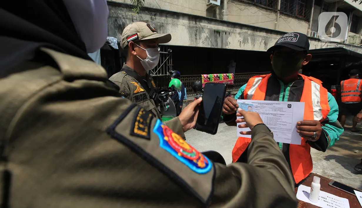 Petugas Satpol PP memotret warga pelanggar razia masker di kawasan Tanjung Duren, Jakarta, Kamis (19/11/2020). Satpol PP terus menindak warga yang melanggar protokol kesehatan selama PSBB transisi dengan sanksi kerja sosial di sarana umum atau membayar denda. (merdeka.com/Imam Buhori)