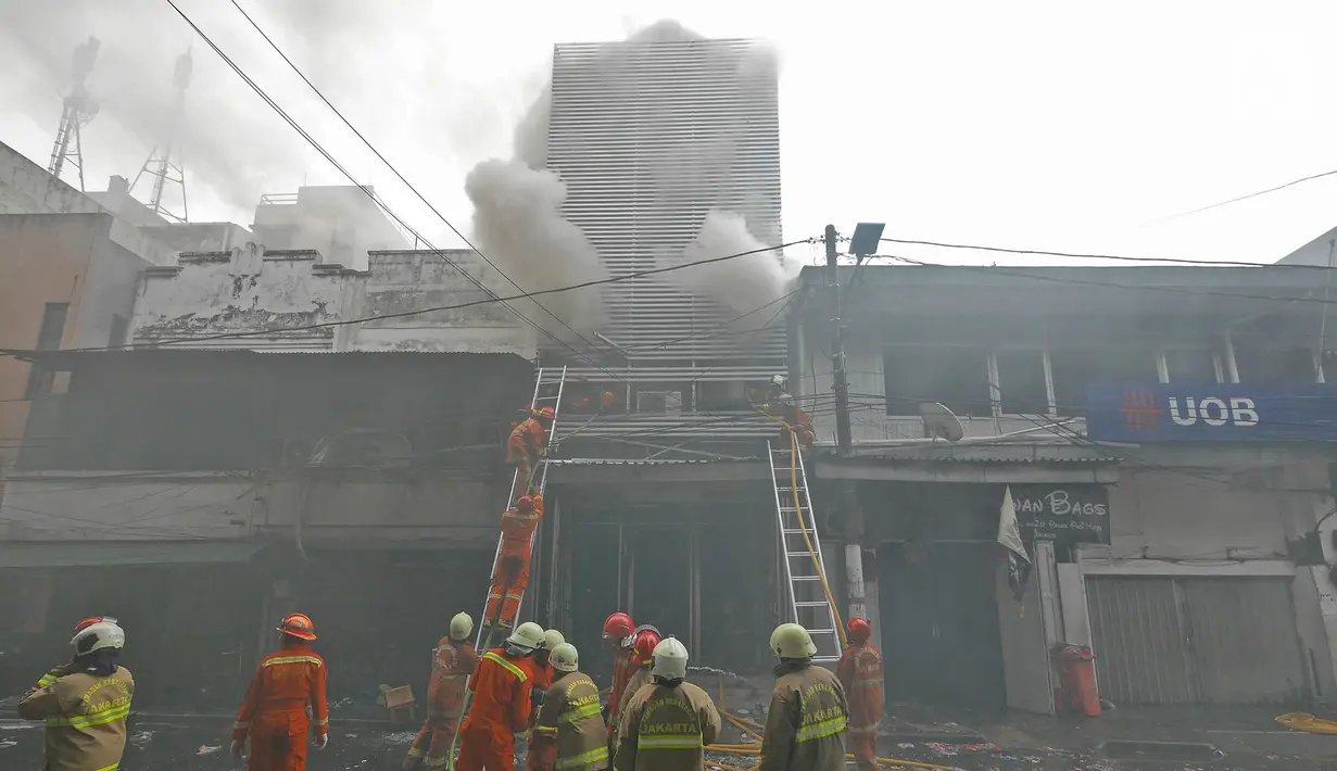 Petugas pemadam kebakaran berusaha memadamkan api yang membakar gudang petasan di jalan Asemka, Jakarta, Jumat (21/6/2019). Sebanyak 27 unit mobil dinas pemadam kebakaran dikerahkan untuk memadamkan gudang penyimpanan petasan itu. (Liputan6.com/Herman Zakharia)