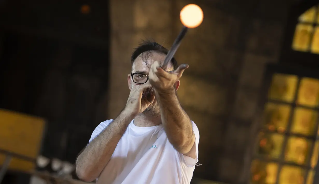 Perajin meniup kaca di pabrik kaca Vidrios Gordiola, Algaida, Pulau Mallorca, Spanyol 27 Agustus 2021. Pemerintah Spanyol pada Juli 2021 mendeklarasikan teknik meniup kaca di Spanyol sebagai Warisan Budaya Tak Benda. (JAIME REINA/AFP)