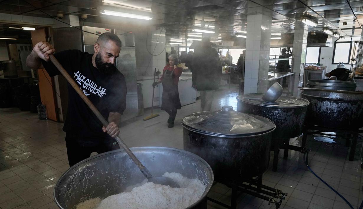 Para sukarelawan memasak makanan untuk para pengungsi yang menghindari serangan udara Israel di Lebanon selatan dan Dahiyeh, di Institut Teknik Bir Hassan yang telah diubah menjadi tempat penampungan, Beirut, Rabu 11 Maret 2026. Ratusan ribu warga Lebanon terpaksa mengungsi dari pinggiran selatan Beirut setelah peringatan evakuasi dan serangan udara Israel. (AP Photo/Bilal Hussein)