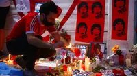 Seorang fans menyalakan lilin untuk Diego Maradona di Buenos Aires, Argentina, Rabu (25/11/2020). legenda sepak bola Argentina itu meninggal dunia pada usia 60 tahun setelah menderita serangan jantung. (AP/Marcos Brindicci)