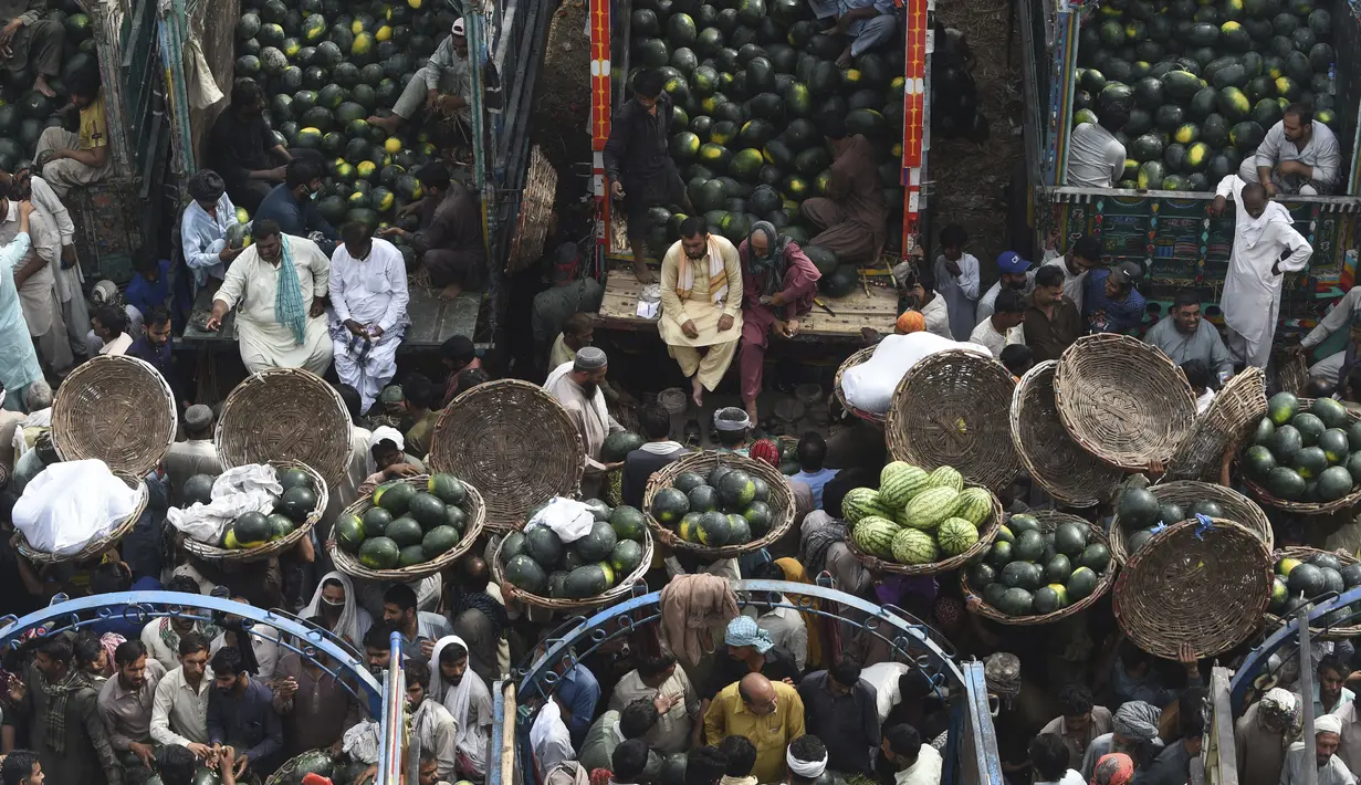 Orang-orang berdagang semangka di pasar buah di Lahore, Pakistan (12/4/2022).  Semangka biasa dipanen buahnya untuk dimakan segar atau dibuat jus. (AFP/Arif Ali)