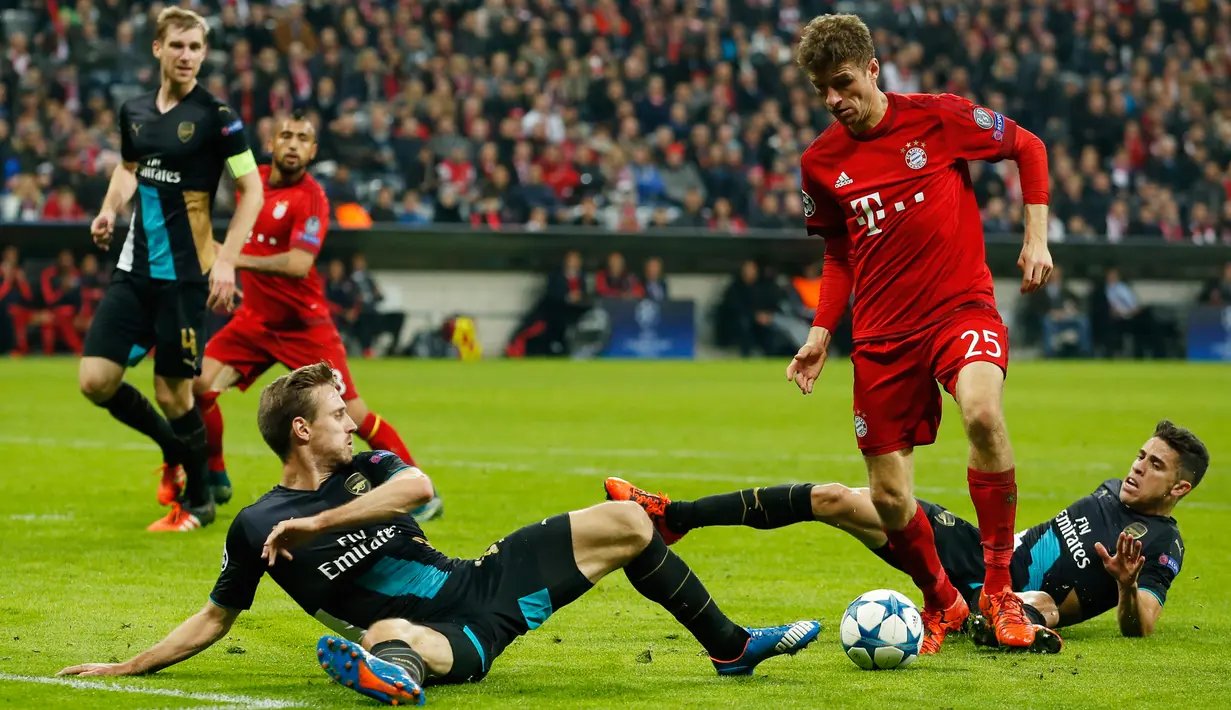 Penyerang Muenchen, Thomas Muller berusaha melewati dua pemain Arsenal pada lanjutan Grup F liga champions di stadion Allianz Arena, Munich, Jerman (4/11). Muenchen menang atas Arsenal dengan skor 5-1. (Reuters/John Sibley) 