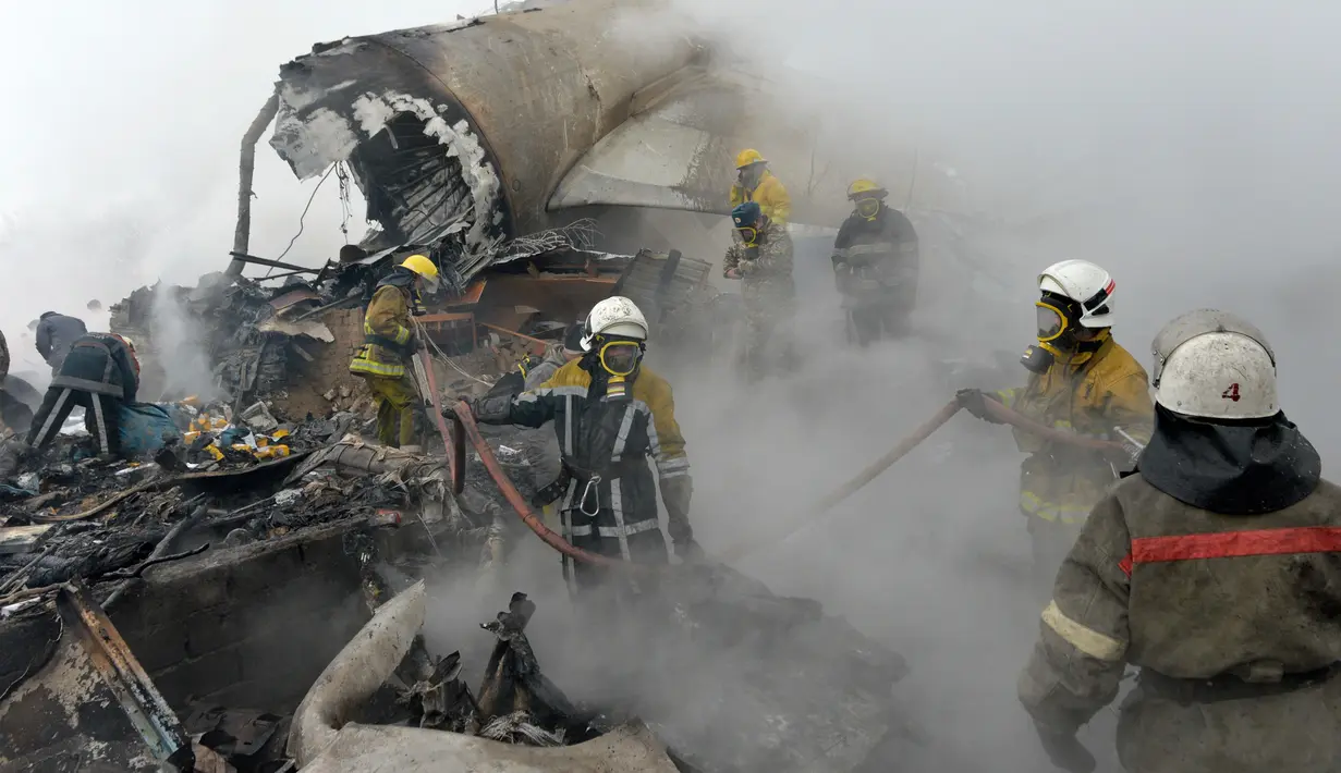Petugas pemadam kebakaran Kyrgyz berhasil memadamkan api diantara sisa-sisa pesawat kargo Turki yang jatuh di daerah perumahan di Bishkek, Kyrgyzstan (16/1). (AP Photo/Vladimir Voronin)