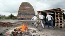 Anak-anak bermain disamping tumpukan palet kayu yang akan digunakan membuat api unggun di Ballymacash, Lisburn, Irlandia Utara (10/7). Acara api unggun ini dikenal juga dengan nama The Eleventh. (AFP Photo/Paul Faith)