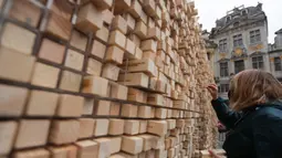 Seorang perempuan mengambil sejumlah balok kayu dari " The Disappearing Wall" di Grand Place, Brussel, Belgia, 3 Oktober 2020. Instalasi seni memperingati 30 tahun reunifikasi Jerman itu terdiri dari 6.000 balok kayu dilengkapi kutipan seniman dan pemikir dari seluruh dunia. (Xinhua/Zheng Huansong)