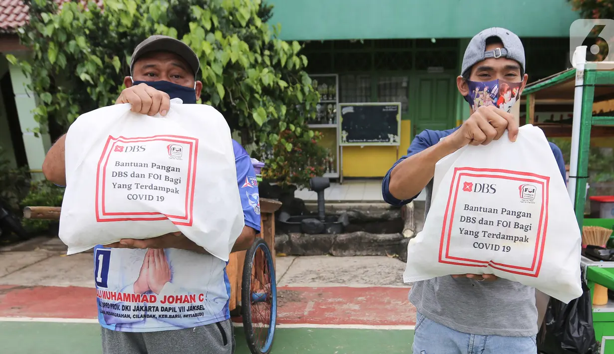Warga terdampak Covid-19 menunjukkan paket makanan yang diterima di Cipulir, Jakarta Jumat (18/12/2020). Bantuan yang diberikan kepada pekerja sektor informal menjadikan total donasi yang diberikan DBS Group untuk Indonesia sebesar IDR27,2 miliar. (Liputan6.com/Fery Pradolo)
